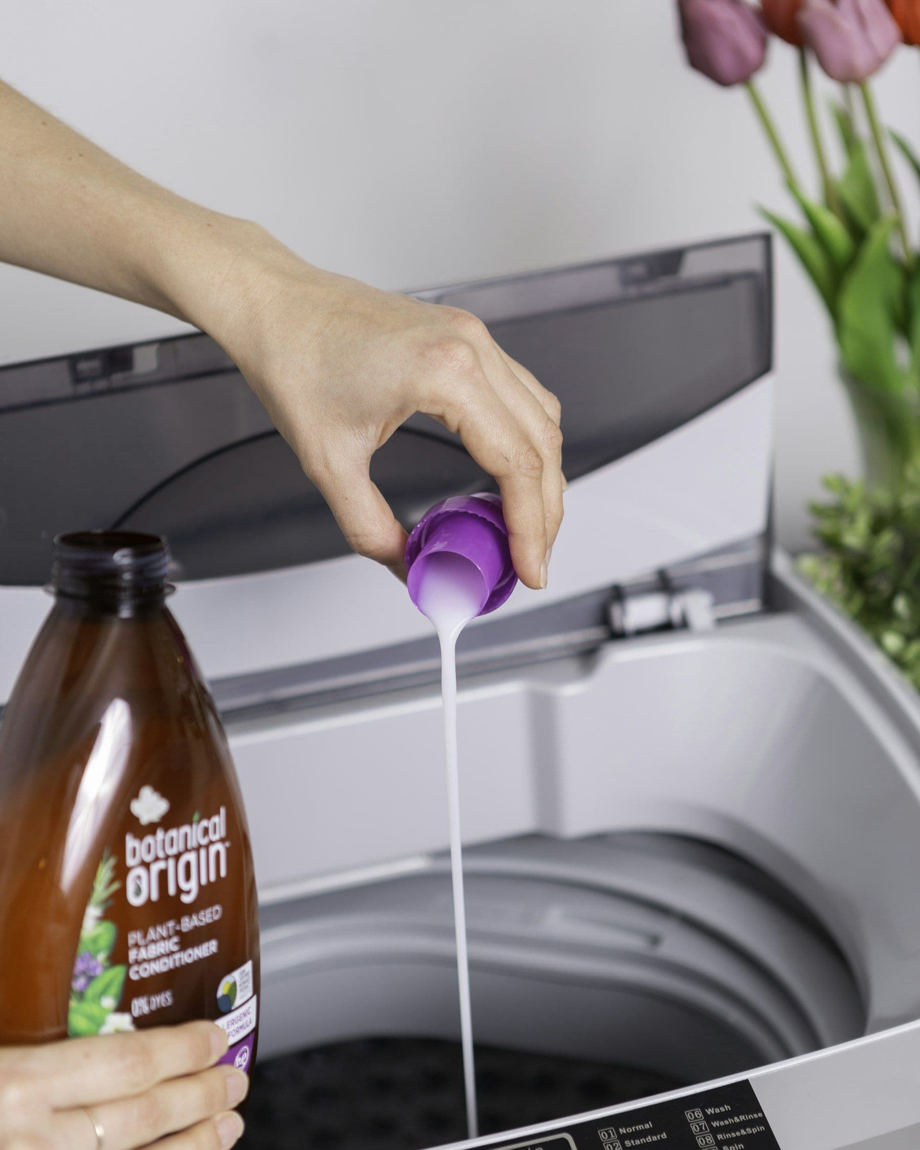 Liquid detergent being poured into a measuring cap over a washing machine
